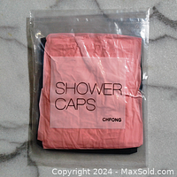 Photo of pink and black shower caps in original clear plastic packaging, stacked together showing label 'SHOWER CAPS' and brand 'CHFONG'.