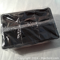 Photo of the ice cube tray wrapped in clear plastic showing the front and top side of the black silicone tray.