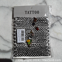 Full packaged set of 12 black tattoo stretch necklaces on a white card labeled TATTOO with assorted colorful small charms.