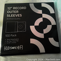 Photo of the front of the package showing 100 pack of 12" record outer sleeves by Hudson Hi-Fi with product details and design.