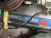 Close-up of Campbell Hausfeld blue label on the air compressor tank with Canadian Series branding and red maple leaf symbol.