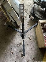 Top view of the full clay target disk thrower showing tripod legs and spring mechanism.