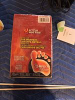 Box of Little Hotties adhesive toe warmers, unopened, red packaging showing foot graphic, 30 pairs, 5 hrs heating