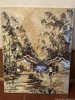 Photo of small village scene painting on canvas with people and cottages.