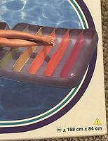 Photo showing the dimensions printed on the inflatable lounge chair (188 cm x 84 cm) and portion of the rainbow design with purple outline.