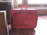 Small red suitcase closed showing front curved black line and clasps