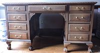 Front view of the wooden desk showing pedestal style with multiple drawers and lion claw feet.