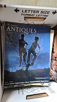 One magazine issue with blue cover featuring a sculpture of two figures against a twilight sky, labeled 'The Magazine Antiques'. Cover topics include French furniture, Daguerreotypes, Folk art, and Shagreen boxes.