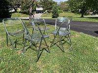 Five vintage folding chairs with clear acrylic seats and backs arranged on grass outdoors, demonstrating the full lot.