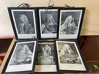 Six vintage framed black and white portrait prints of historical male figures in formal judicial and aristocratic attire arranged on a surface.