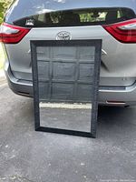 Front view of the rectangular bathroom mirror showing the black textured frame and clear glass.