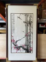 Full view of the framed Chinese ink painting print showing bamboo, pink blossoms, calligraphy, matting, and gold-tone frame.