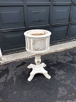 Front view of the white vintage plant stand with tin flower pot showing the base and pot structure.