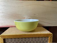 Large yellow CorningWare Pyrex bowl viewed from the side, showing smooth yellow exterior and white interior.