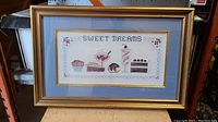 Full view of framed woven textile artwork titled 'Sweet Dreams' showing framed dessert motif.