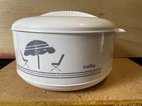 Front view of white plastic insulated cooler container with a beach umbrella and chair graphic and 'cello' logo.