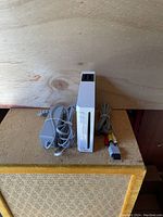 Front view of Nintendo Wii console with power supply and AV cable on wooden surface