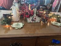 View of the Christmas decor items arranged on a wooden table showing garland, candle holders, berry decorations, coasters, and card caddy.