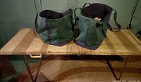 Vintage wooden folding table with rusted metal legs, two green L.L. Bean canvas tote bags on top