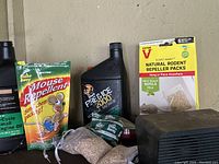 Various pest control products including mouse repellent pack, Victor natural rodent repellent packs, Free Ice 3000 fuel stabilizer, and granule packs, all on a surface against a wall.