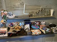 Overview of kitchen items on counter and shelves including Pyrex bowls, pie birds, baking pans, cookie press, canisters, and some packaged goods.