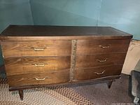 Photo of the mid-century modern wooden dresser with six drawers, curved fronts, and tapered legs, showing condition and design details.