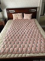 View of Paris themed pink quilt and two matching pillows on bed showing overall condition and color.