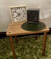 Photo of square wooden table with vintage Elgin clock, black Micro Furnace heater, and round green doily on top