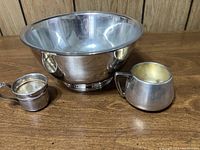 Photo showing the Oneida Paul Revere silverplate bowl and the two sterling silver baby cups standing beside it on wooden surface.
