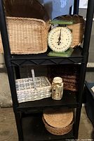 Shelf with seven assorted woven baskets in various shapes and sizes, vintage green American Family Scale, and decorative painted Mason jar