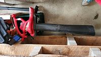 Full view of the red Toro Ultra blower vac with black collection tube and attached collection bag on the floor of a garage.