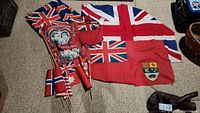 Photo showing two large red flags with Union Jack and Ontario provincial shield, several small hand-held Union Jack flags, and a red 'Coronation' flag with two faces.