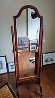 Front view of full length mirror showing arched wood frame, reflective surface and finial post design.