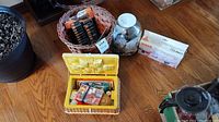 Photo showing yellow sewing basket with assorted sewing notions inside, a glass jar of buttons, a basket with batteries, and the bunny night light on a wooden surface.
