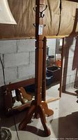 Full view of the wooden coat tree rack showing its height and base design.