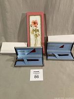 Entire lot: two Uni-Ball Exceed pens in open cases with outer sleeves and floral letter case