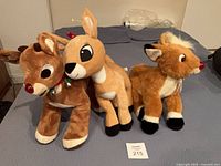Three plush reindeer lined up on bed