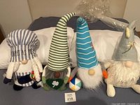 Group shot of all four themed plush gnomes on bed