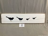 Full view of wooden plaque showing four bird silhouettes and white background