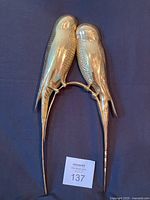 Full view of brass parrot wall art on dark background