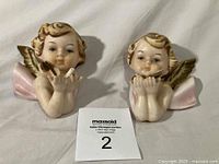 Both ceramic cherub wall hangings front view