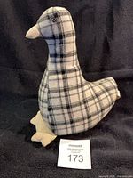 Side view of plaid fabric duck doorstop on black background