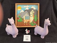 Lot overview showing wall art, two ceramic llamas, felt llama