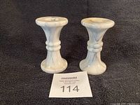 Front view of both marble candlesticks standing upright on dark fabric