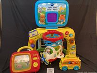 All four toys grouped: VTech sports center, PlayGo TV, Fisher-Price airplane, Sesame Street bus