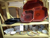 Overview of all dishes and trays on shelf showing various ceramic bowls, plates, chopsticks, and wooden trays