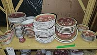 Overview of multiple stacks of matching plates, bowls, spoons on metal shelf
