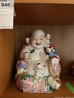 Front view of Chinese porcelain Laughing Buddha figurine with five children, colorful robes, and beaded necklace.