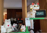 Two shelves with assorted cat figurines and cat wall art, showing the full lot arrangement.