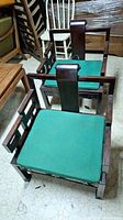 Two matching Asian style chairs with dark wood finish and green cushions, showing chairs from front at slight angle and surroundings.